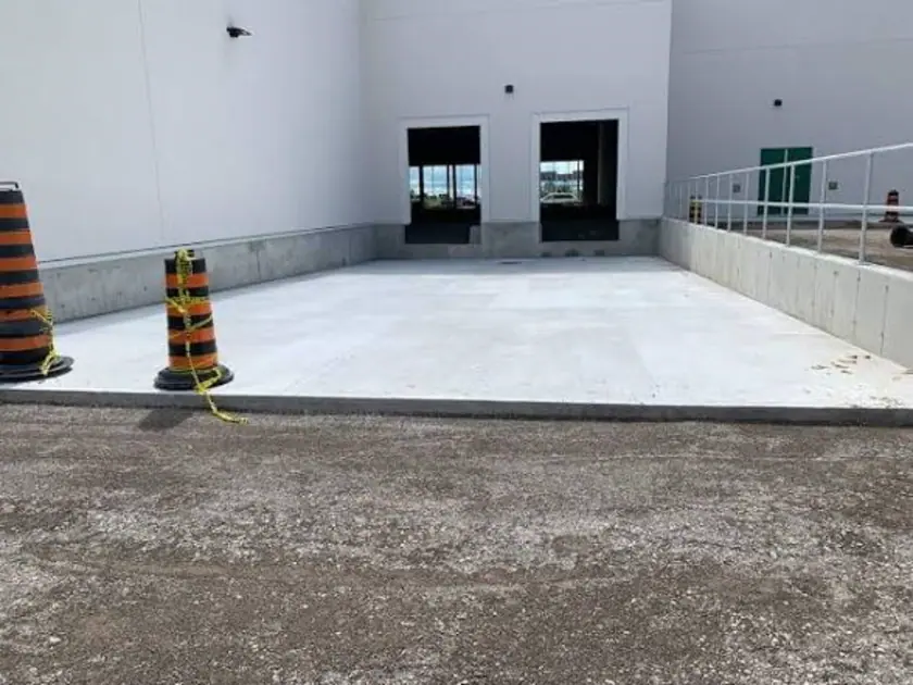 Clean finished recessed commercial loading-dock concrete slab with two open doors